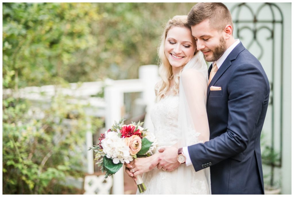 rustic vintage inspired wedding Charlottesville B & B fall Wedding  bride and groom outdoors with picket fence in background and bridal bouquet in focus