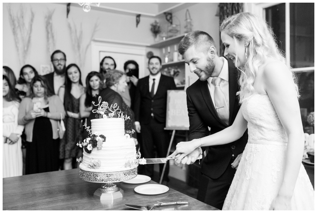 charlottesville bed and breakfast fall september wedding bride and groom cutting two tiered cake black and white candid photo intimate wedding reception