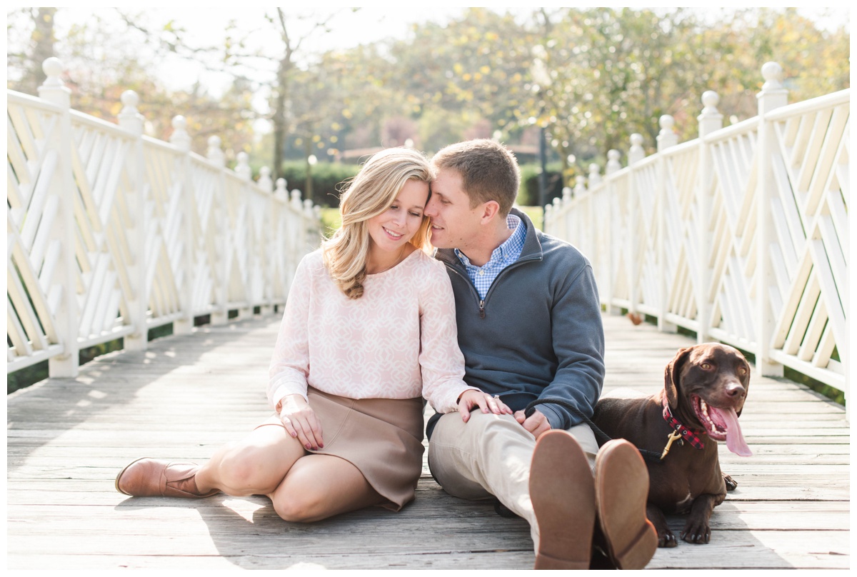fall engagement photos at quiet waters park in annapolis by annapolis wedding photographer sarah & dave photography couple sitting on bridge with dog
