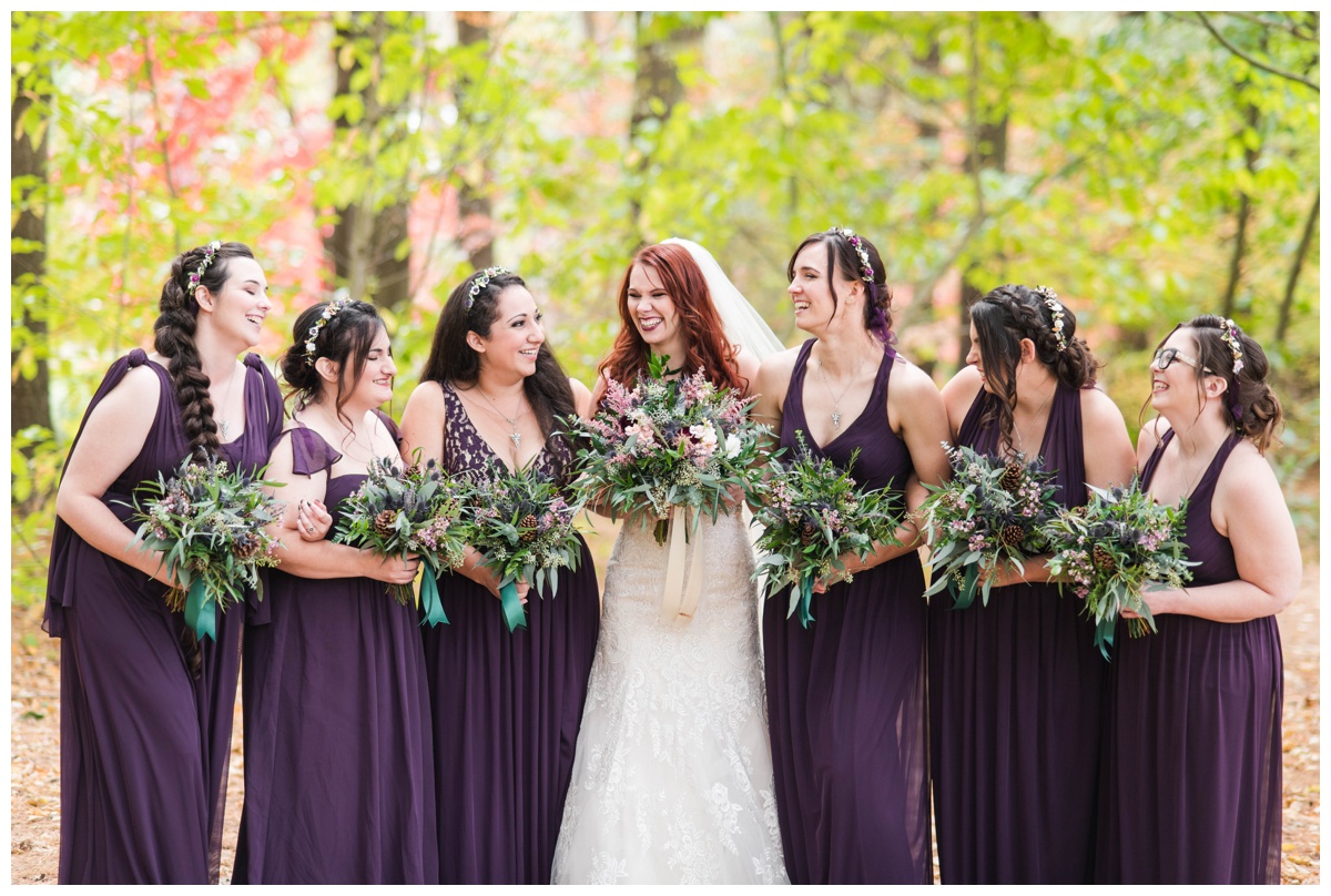 Whimsical Woodland Fall Wedding at mountain memories at thorpewood in thurmont maryland in october by sarah & dave photography richmond wedding photographer deep dark purple bridesmaid dresses holding bouquet wedding party photos with bride formal portrait ideas bridal party laughing candid photo outdoors