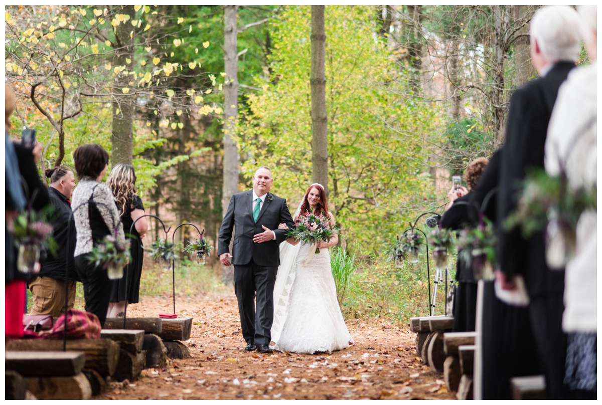Whimsical Woodland Fall Wedding at mountain memories at thorpewood in thurmont maryland in october by sarah & dave photography richmond wedding photographer forest inspired outdoor ceremony in the woods bride and father of the bride walking down aisle log tree stump seating seats