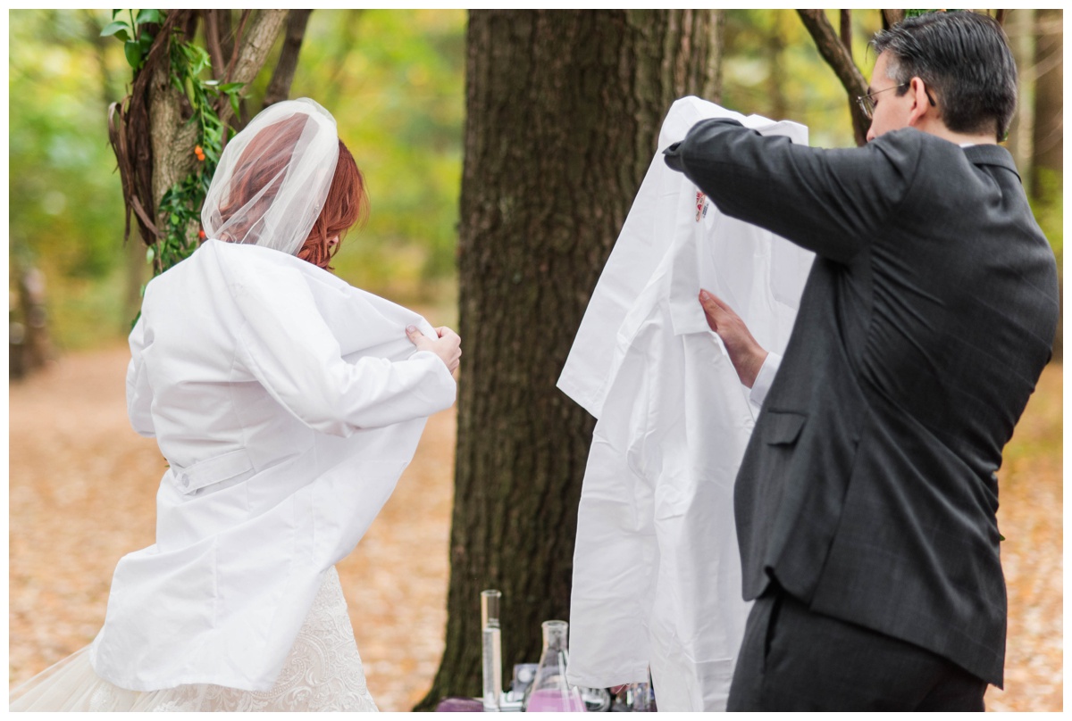 Whimsical Woodland Fall Wedding at mountain memories at thorpewood in thurmont maryland in october by sarah & dave photography richmond wedding photographer forest inspired outdoor ceremony in the woods unity candle alternative science inspired unity ceremony bride and groom putting on lab coats test tubes and goggles on table nearby