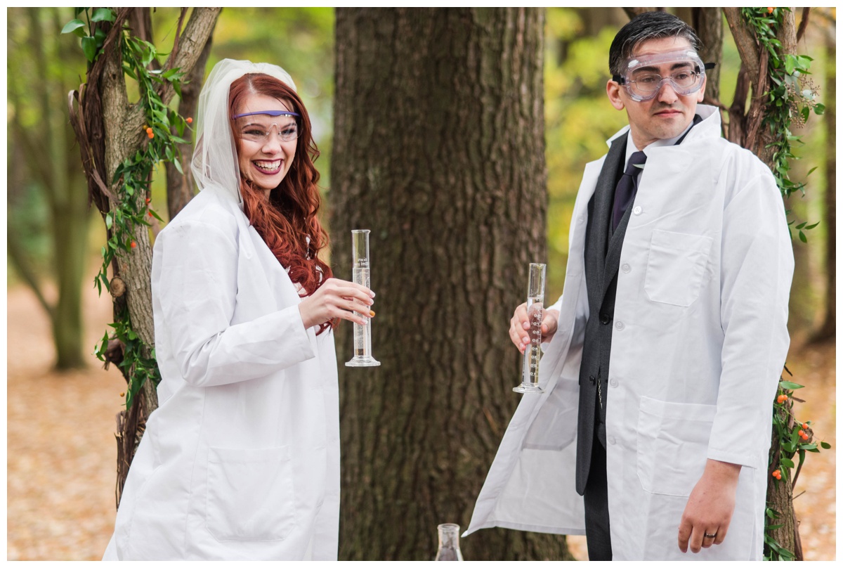 Whimsical Woodland Fall Wedding at mountain memories at thorpewood in thurmont maryland in october by sarah & dave photography richmond wedding photographer forest inspired outdoor ceremony in the woods unity candle alternative science inspired unity ceremony bride and groom wearing lab coats goggles holding test tubes science experiment