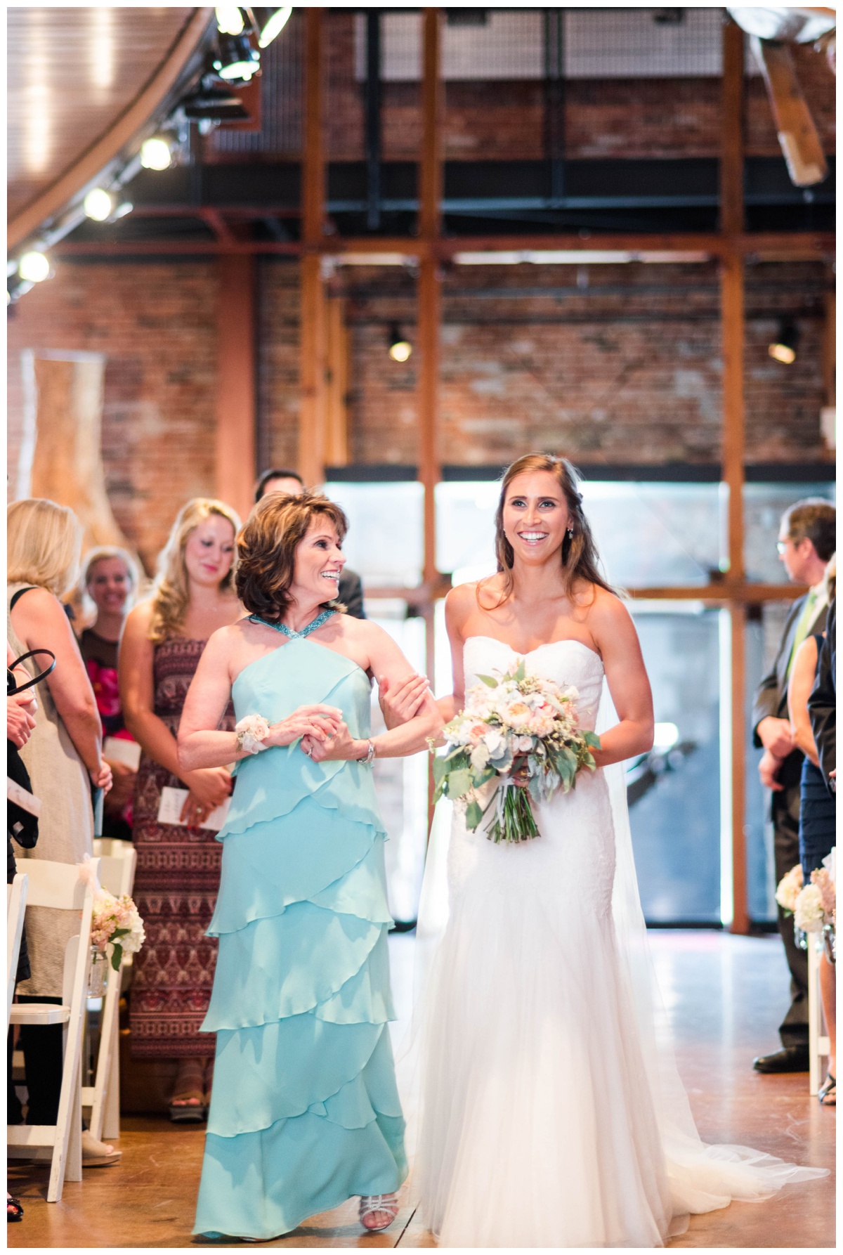 american visionary art museum wedding in baltimore maryland by richmond wedding photographer sarah & dave photography pink coral peach wedding colors summer wedding bride walking down aisle with mother looking at her daughter holding arms