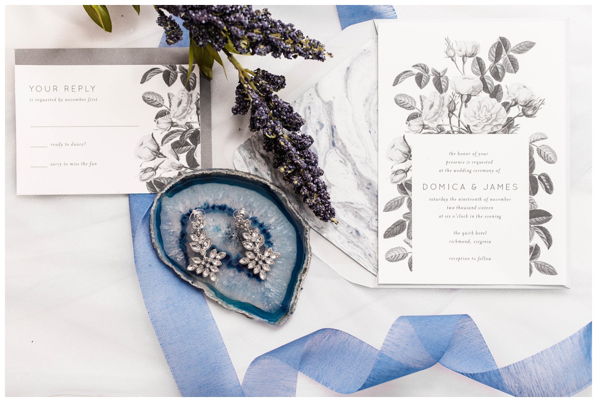 shades of blue wedding inspiration at quirk hotel in richmond virginia by rva wedding photographer sarah & dave photography bride and groom sitting on iconic quirk hotel couch rva virginia wedding blue wedding inspo ideas invitation suite trio grayscale black and white florals print marble accents paper with bridal jewelry and geode