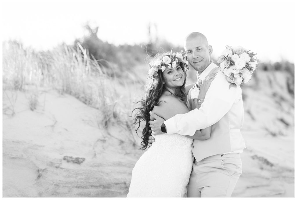 black and white beach wedding photo of bride and groom in front of sand dunes