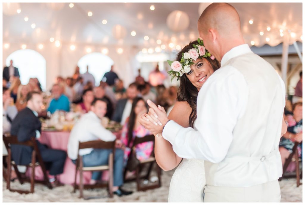 photo of couple dancing with their first dance at delaware beach wedding with paper lanterns and pink wedding reception decorations outside in the sand