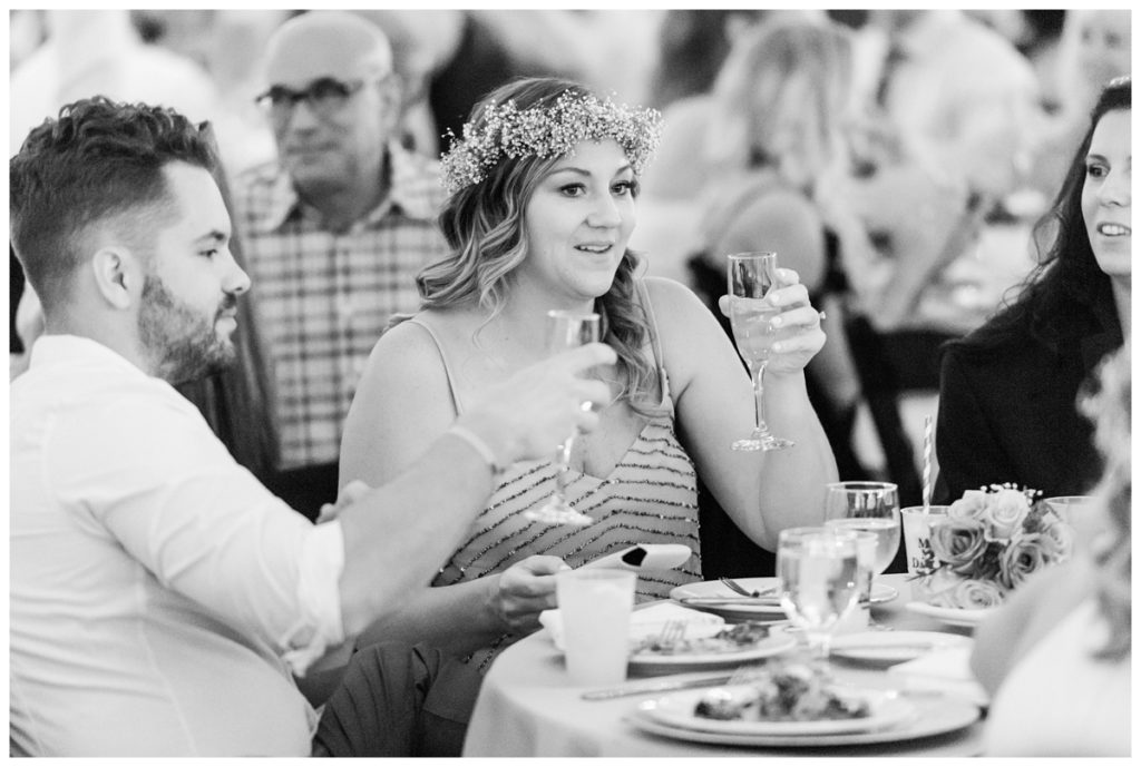 wedding reception photo of guests holding glasses and bridesmaid wearing flower crown and smiling