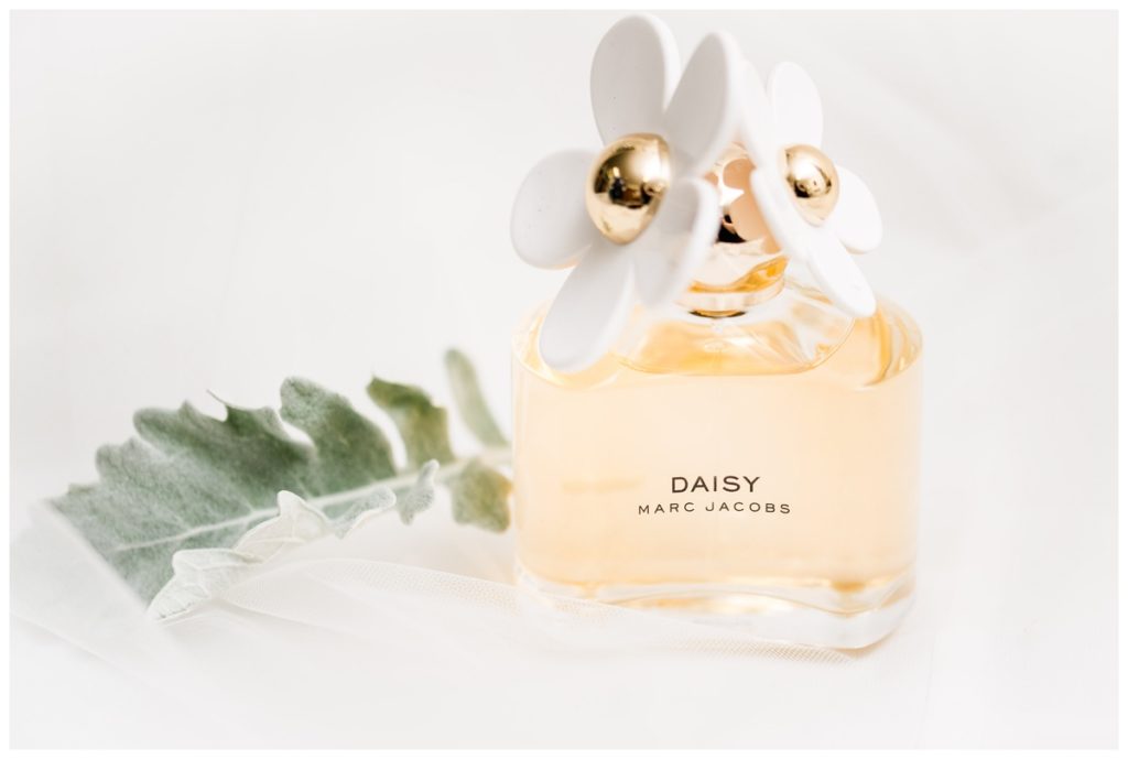 marc jacobs "daisy" perfume with greenery and toile photo