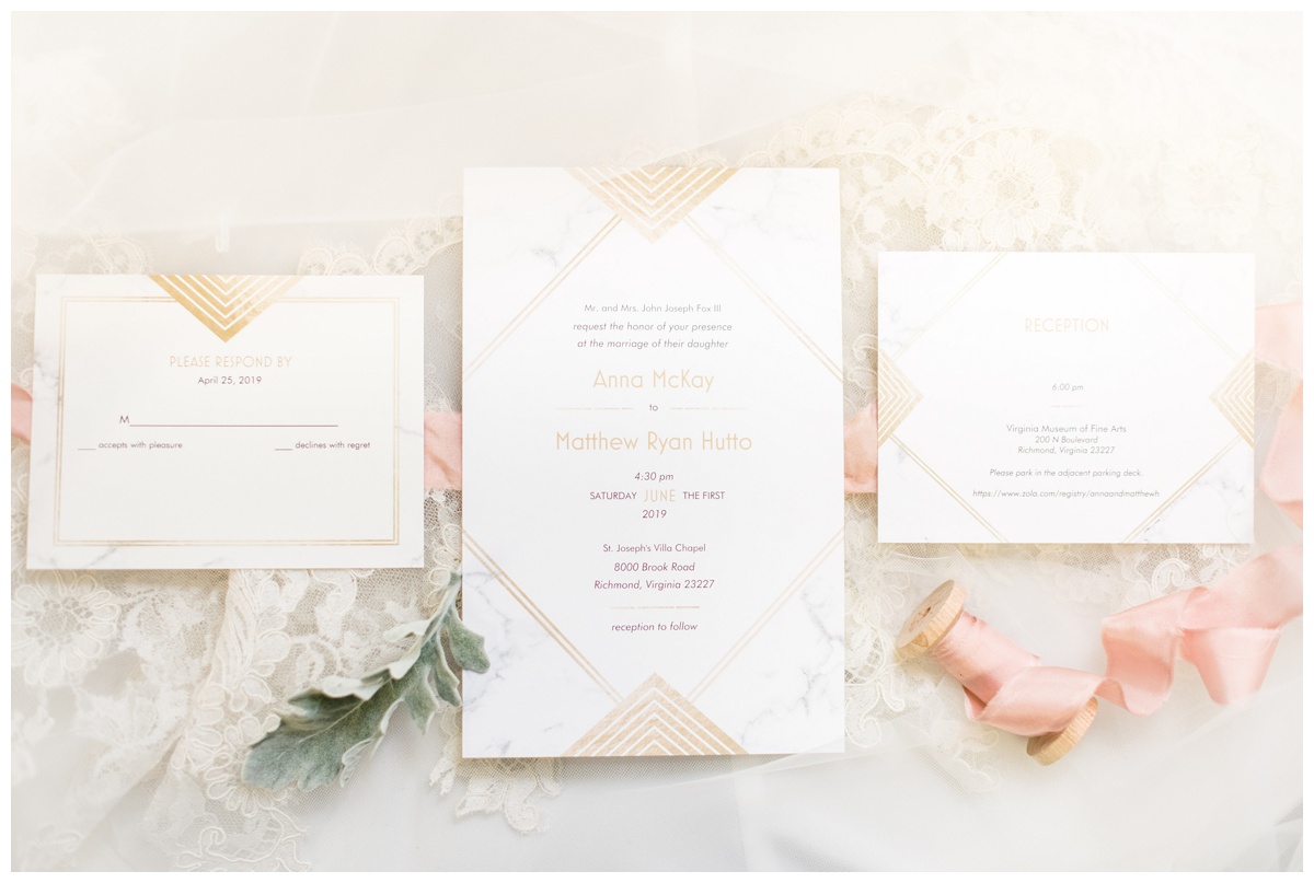 gold and pink geometric wedding invitation set with pink ribbon and white flowers and lace flatlay