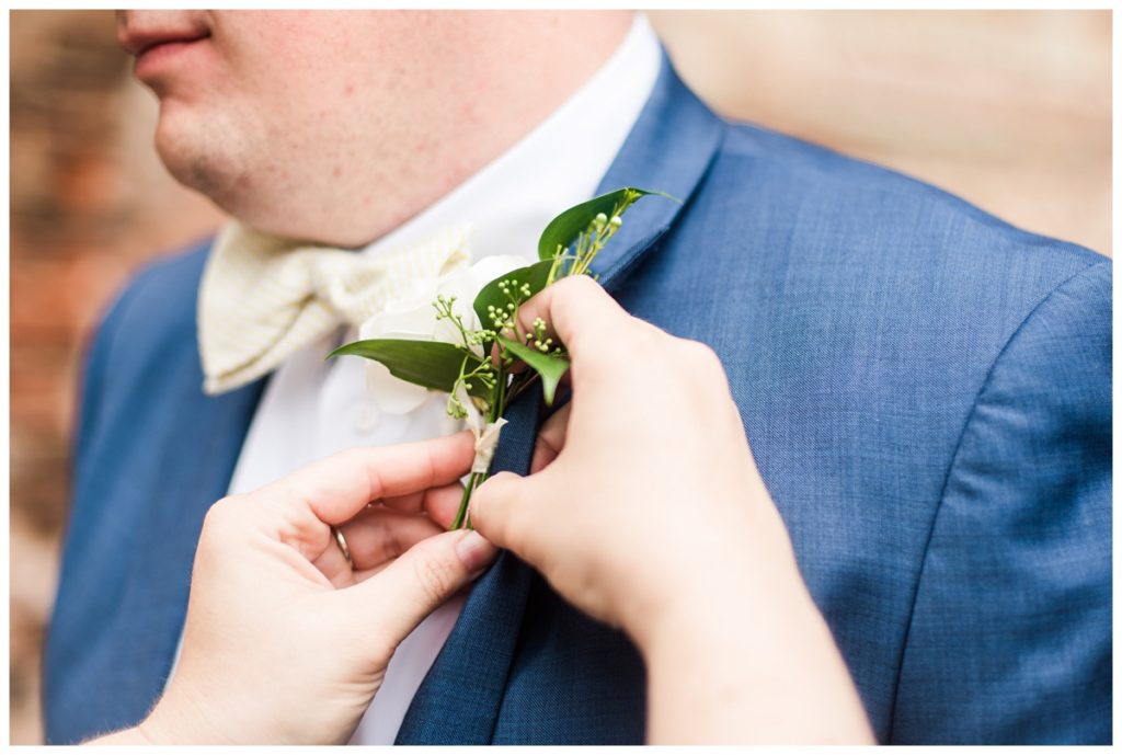 closeup of elegant greenery and white boutonniere, indigo blue menguin tuxedos for groom, and pale yellow and white striped bow tie - chris's attire was perfect for his civil war museum wedding in the summer
