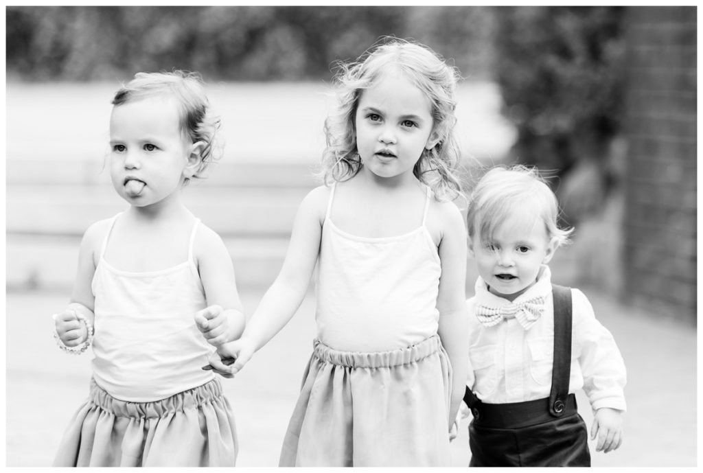charming summer wedding at the civil war museum and historic tredegar in june - richmond virginia rva wedding photographer, sarah & dave photography - photo of ceremony decor - flower girls wearing flowy light grey skirts and white tops and ringbearer wearing indigo dark blue romper shorts outfit with suspenders and button up white shirt - so adorable!!! - black and white photo