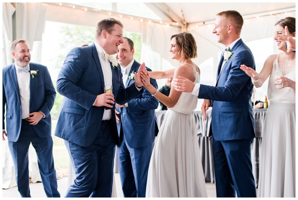 high fiving the groom as he walks into the wedding reception smiling