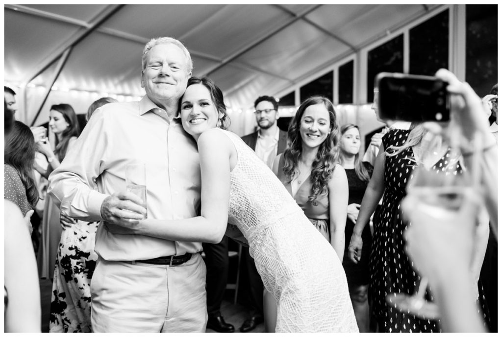 photo of bride and her dad smiling and hugging and someone taking a photo of them with their phone