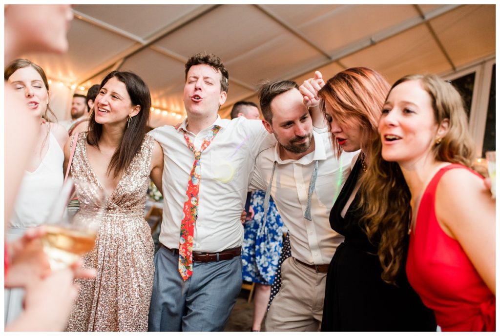 photo of people dancing, singing, and smiling at wedding reception
