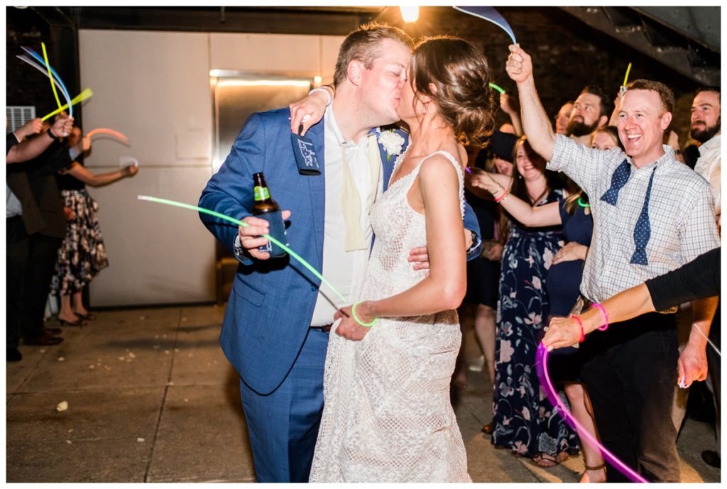 glow stick send off at the end of wedding reception - bride and groom kissing - bride is holding koozie wedding favor - charming summer wedding at the civil war museum by richmond va rva wedding photographer sarah & dave photography