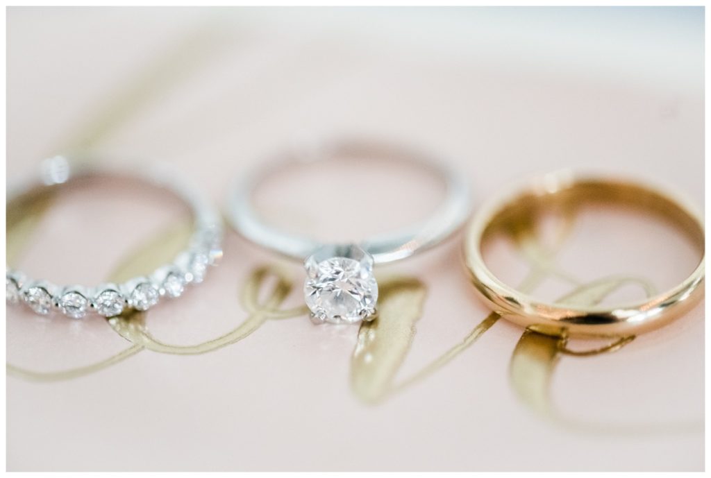 wedding rings photo - wedding ring trio - against gold "love" lettering on wedding invites