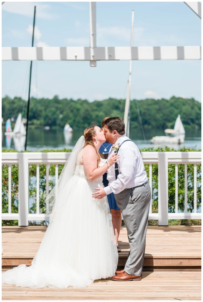 first kiss as a married couple with blue skies and sailboats in the backdrop