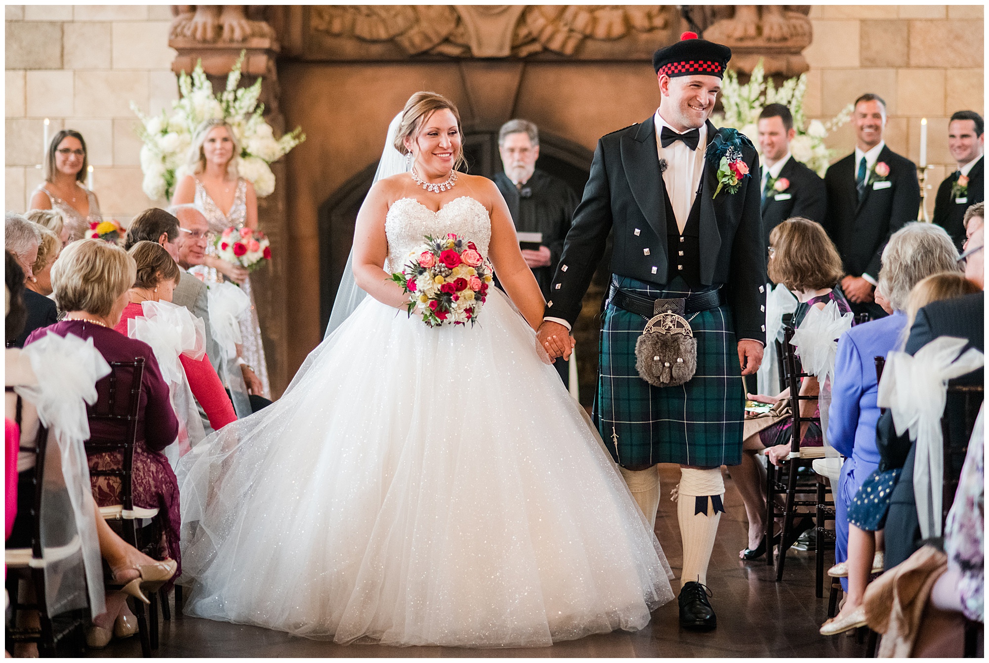 just married photo. bride and groom holding hands and walking down the aisle. groom is wearing kilt and tartan. bride is wearing princess cut ballgown wedding dress that is sparkly. dover hall estate ballroom venue is in the backdrop. by richmond wedding photographer, Sarah & Dave Photography