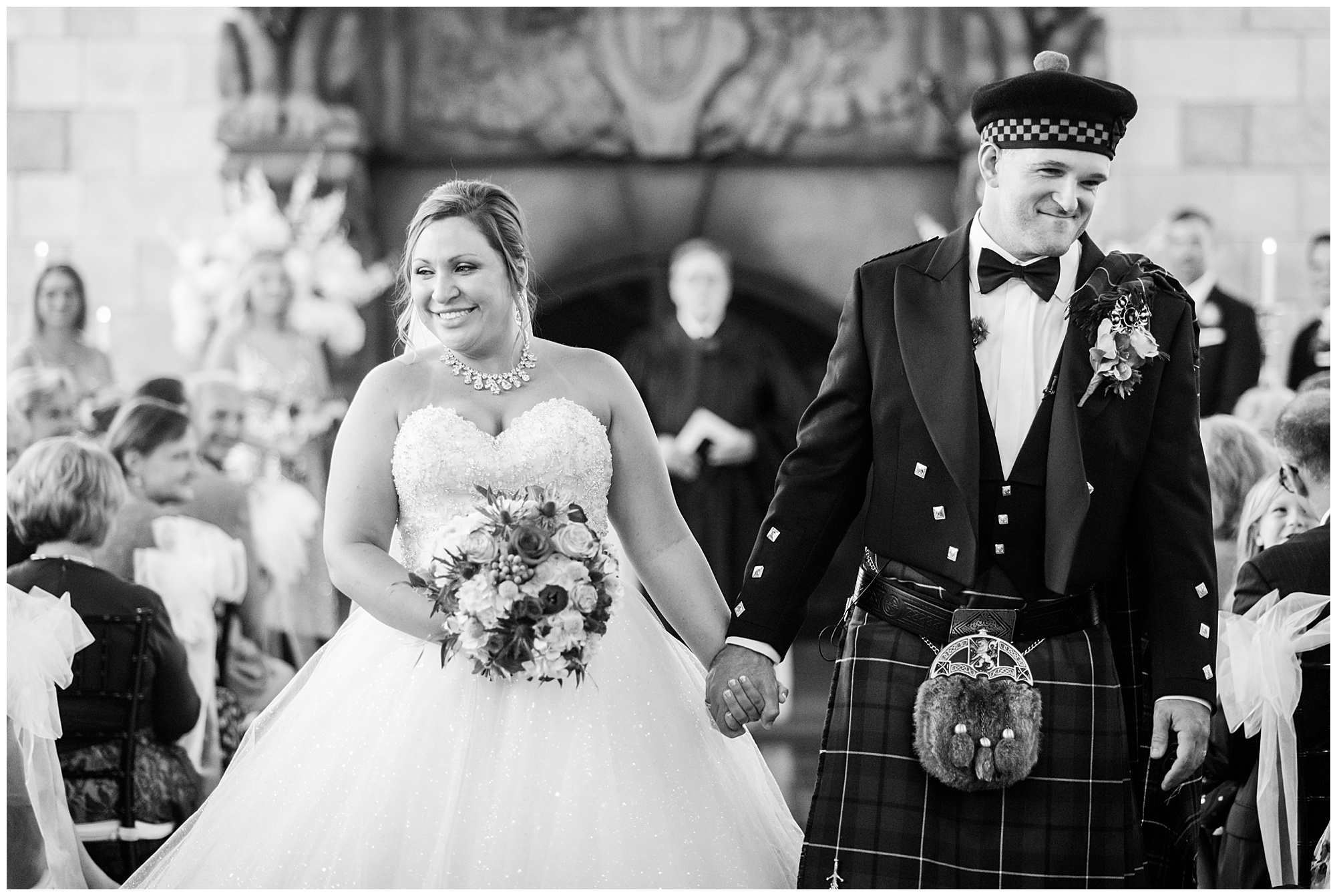 just married photo. bride and groom holding hands and walking down the aisle. groom is wearing kilt and tartan. bride is wearing princess cut ballgown wedding dress that is sparkly. dover hall estate ballroom venue is in the backdrop. by richmond wedding photographer, Sarah & Dave Photography